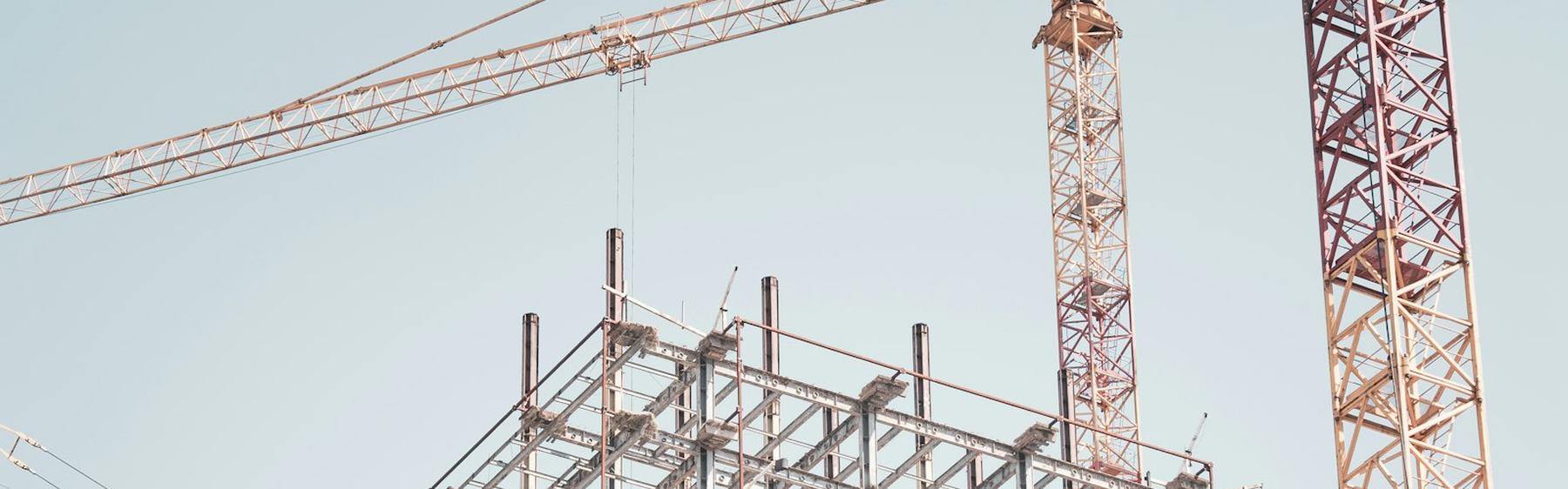 Tower cranes over a steel frame rising on a city construction site