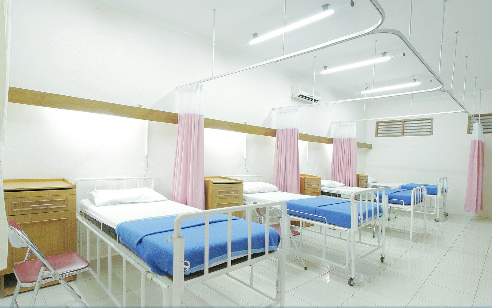 Clean hospital ward with made beds and curtained bays