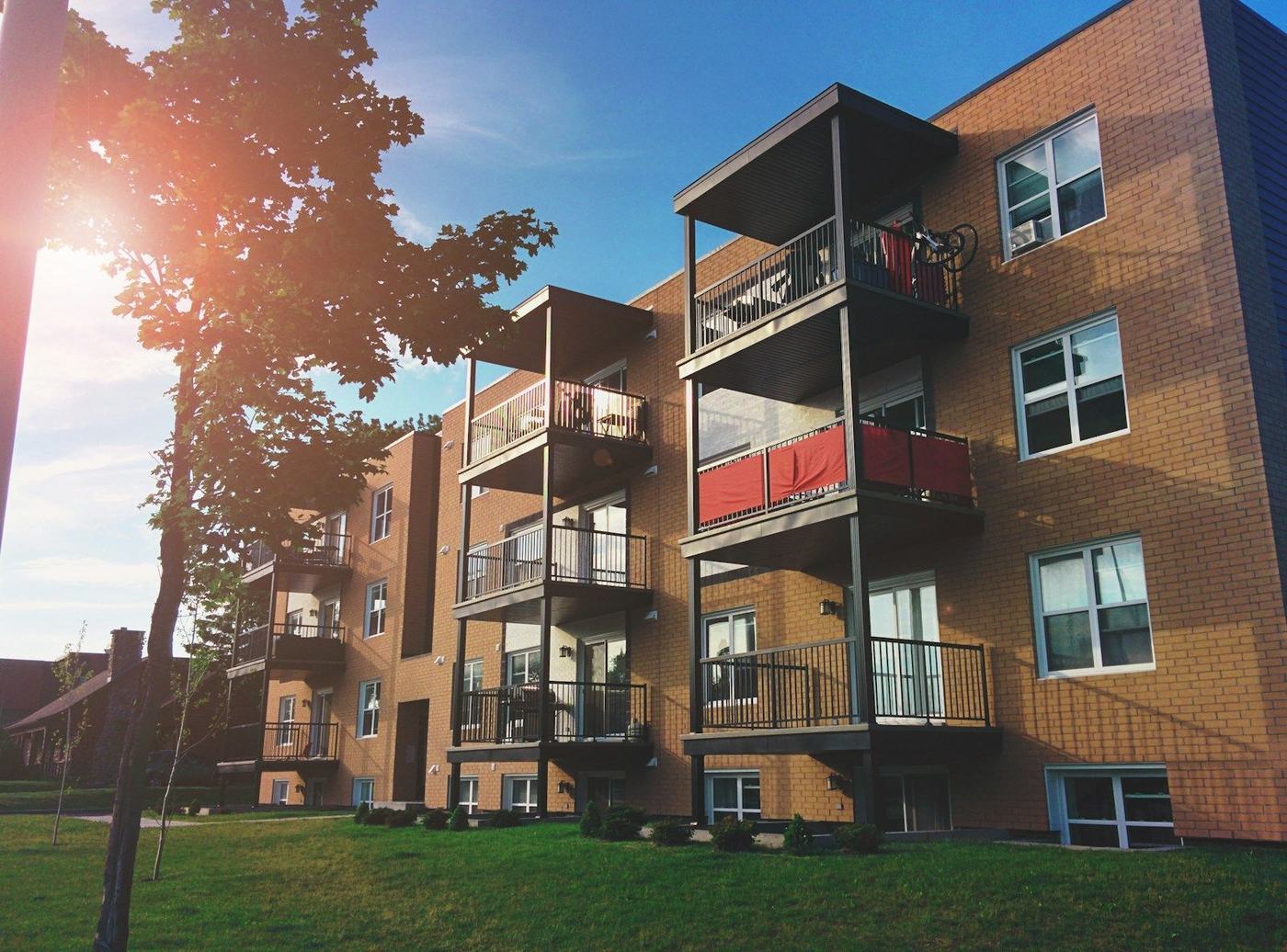 Apartment buildings with balconies around a landscaped lawn