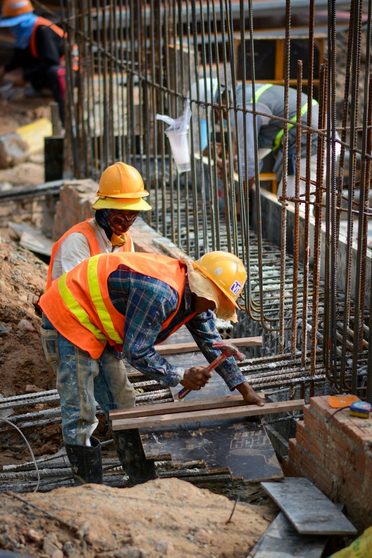 Site workers in hard hats and high-visibility vests fixing reinforcement steel