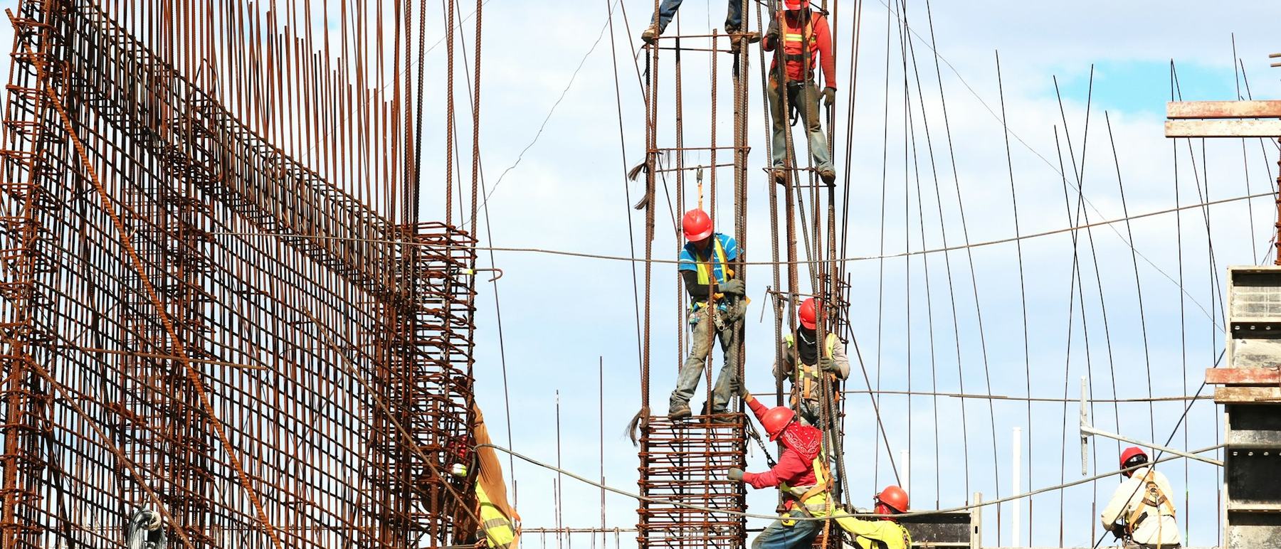Workers placing reinforcement steel across a large construction site